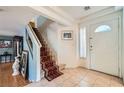 Inviting foyer showcasing a staircase with a red carpet runner and tiled flooring at 8476 Tackle Box Ct, Las Vegas, NV 89113