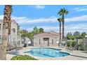 Community pool area featuring lounge chairs, palm trees, and a charming pool house at 9470 Peace Way # 233, Las Vegas, NV 89147