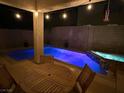 Backyard oasis featuring a pool with brilliant blue lighting, hot tub, covered patio, and outdoor dining set at 1011 Pecos River Ave, Henderson, NV 89002