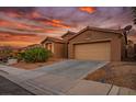 Desert home at sunset features a tan exterior, attached garage, and drought-resistant landscaping at 10513 Shanna Trellis Ave, Las Vegas, NV 89144
