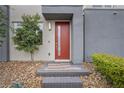 Stylish front door with a red finish, complemented by manicured landscaping and stone accents at 11325 Gravitation Dr, Las Vegas, NV 89135