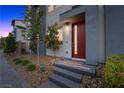 A modern front entrance featuring a red door, gray siding and a landscaped walkway at 11325 Gravitation Dr, Las Vegas, NV 89135
