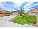 Beautiful single story home featuring desert landscaping, green grass and a spacious driveway at 2561 Cosmic Dust St, Henderson, NV 89044