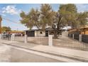 Street view of a single-story home featuring secure black fencing and desert landscaping at 2958 Al De La St, Las Vegas, NV 89146