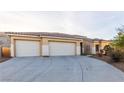 Home's front exterior featuring a three-car garage and desert landscaping at 3439 Cottage Canyon St, Laughlin, NV 89029