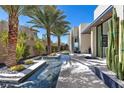 Modern home exterior featuring a water feature, desert landscaping, and sleek architectural design at 535 Serenity Point Dr, Henderson, NV 89012