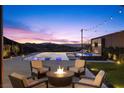 Outdoor seating area with a fire pit overlooking an infinity pool at dusk with city views at 535 Serenity Point Dr, Henderson, NV 89012
