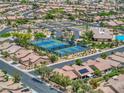 Residential aerial view highlighting community tennis courts, clubhouse, pool, and tree-lined streets and houses at 6076 Wheat Penny Ave, Las Vegas, NV 89122