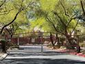 A gated community entrance featuring mature trees and landscaping at 10067 Sand Key St, Las Vegas, NV 89178