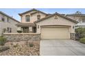 Inviting two-story home with a two-car garage, desert landscaping, and a decorative stone front wall at 10808 Wallflower Ave, Las Vegas, NV 89135