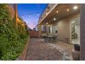 Inviting outdoor patio with brick flooring, string lights, and lush greenery for relaxing evenings at 3268 Grayson Lake Ct, Las Vegas, NV 89129
