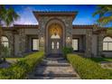 Welcoming front entrance with arched doorway, stone accents, and manicured landscaping at 7687 W Pebble Rd, Las Vegas, NV 89113
