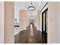 Hallway with dark hardwood flooring, columns and chandelier lighting at 9 Greely Club Trl, Henderson, NV 89052