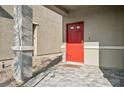 Close up of the front door of the house with a red door, stone columns, and a stone tile entryway at 9068 Lennon Ln, Las Vegas, NV 89113