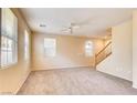 Spacious carpeted living room with natural light and a staircase at 9115 Canoga Canyon Ct # 102, Las Vegas, NV 89149