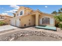 Attractive two-story home with a three-car garage, a welcoming porch, and desert-style rock landscaping at 10021 Skipper Ct, Las Vegas, NV 89117