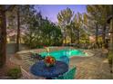 Backyard pool and spa with a brick patio, outdoor seating, and lush landscaping at 4156 Balmoral Castle Ct, Las Vegas, NV 89141