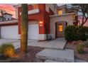 Charming two-story home with a well-manicured desert landscape and three car garage with a walkway to the front door at 8516 Montago Valley Ave, Las Vegas, NV 89117