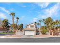 Charming two-story home featuring a tile roof, an attached garage, and well-manicured landscaping with mature palm trees at 125 Firecreek Cir, Las Vegas, NV 89107