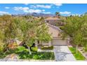 An aerial view of a well-maintained home with desert landscaping, tile roof, and mountain views at 3057 Sunrise Heights Dr, Henderson, NV 89052