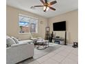 Bright living room with neutral color palette, large window, and tile flooring at 5667 Foxglove Field St, Las Vegas, NV 89130