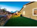 Green backyard features artificial turf, stone retaining wall, and outdoor lighting ideal for entertainment at 10125 Sequoia Falls Pl, Las Vegas, NV 89149