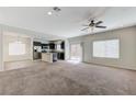 Spacious open-concept living room with plush carpet, sliding glass doors, and a modern ceiling fan at 2617 Romarin Ter, Henderson, NV 89044