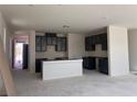 A new kitchen with dark cabinets, a white island, and an open floor plan at 9989 River Corral St, Las Vegas, NV 89166