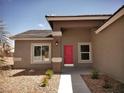 Welcoming front entrance featuring a red door, modern lighting, and desert landscaping at 1931 Rose Ct, Pahrump, NV 89048