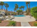 Community pool with lounge chairs and a waterfall feature, surrounded by lush landscaping at 5412 Harmony Green Dr # 101, Las Vegas, NV 89149