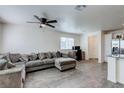 Spacious living room featuring modern gray sofa, ceiling fan, and wood-look flooring, bathed in natural light at 6804 Surf Green Ct, North Las Vegas, NV 89086