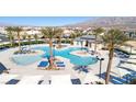 Stunning community pool with palm trees and lounge chairs, perfect for relaxation and recreation at 6804 Surf Green Ct, North Las Vegas, NV 89086