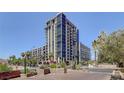 Modern high-rise building with expansive glass windows, multiple balconies, and lush landscaping in an urban setting at 353 E Bonneville Ave # 754, Las Vegas, NV 89101