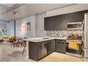 Open-concept kitchen with stainless steel appliances, gray cabinetry, tile backsplash, and a breakfast bar overlooking the living area at 353 E Bonneville Ave # 754, Las Vegas, NV 89101