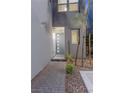Front door with modern sidelights and hardware surrounded by rock landscaping and walkway at 11315 Gravitation Dr, Las Vegas, NV 89135