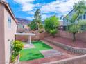Landscaped backyard features a covered patio, artificial grass, and desert landscaping at 189 Kings Canyon Court Ct, Henderson, NV 89012