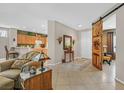 Spacious living room featuring tile floors, with open access to kitchen, dining and decorative barn door at 2429 Wisconsin Dells Dr, Henderson, NV 89044