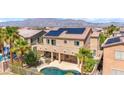 Aerial view of a backyard featuring a refreshing pool, patio area, palm trees, and solar panels on the roof at 6917 Puetollano Dr, North Las Vegas, NV 89084