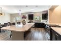 Modern kitchen featuring stainless steel appliances, a large island, sleek black cabinets, and hardwood flooring at 8179 Shale Canyon St, Las Vegas, NV 89139