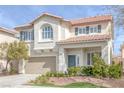 Charming two-story home featuring a tan stucco exterior, arched window, and a well-manicured front yard at 10004 W Cherokee Ave, Las Vegas, NV 89147