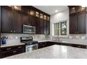 Updated kitchen featuring dark wood cabinets, stainless steel appliances, and light granite countertops at 10356 Addie De Mar Ln, Las Vegas, NV 89135