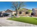 Attractive single-story house showcasing tidy landscaping with stone, artificial turf, and a healthy shade tree at 5578 River Highlands Pl, Las Vegas, NV 89122
