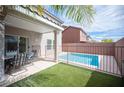 Inviting backyard featuring a small pool, covered patio with dining set, and well-maintained artificial grass at 9277 Valley Ranch Ave, Las Vegas, NV 89178