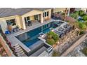 Aerial view of backyard featuring a large swimming pool with spa, seating, lush landscaping, and a built-in grill at 19 Hilltop Crest St, Henderson, NV 89011