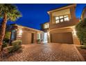 Beautiful two-story home with a three-car garage and brick driveway at dusk at 19 Hilltop Crest St, Henderson, NV 89011