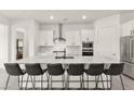 Modern white kitchen featuring a large marble waterfall island with seating for six at 31 Autumn Palm Ave, Henderson, NV 89011