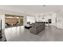 Open-concept living room with gray sectional, tile floors, and sliding glass doors to the backyard at 31 Autumn Palm Ave, Henderson, NV 89011