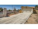 Wide concrete driveway leading to a two-car garage, framed by a block wall and desert landscaping at 100 Underhill Ct, Las Vegas, NV 89145