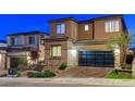 Modern two-story home at dusk, featuring a brick facade and a contemporary glass garage door at 12439 Iron Bluff Ave, Las Vegas, NV 89138