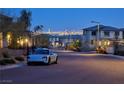 Residential street view featuring a modern blue car parked near homes with city lights in the background at 12439 Iron Bluff Ave, Las Vegas, NV 89138